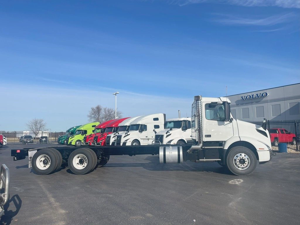Side view of a white Volvo VNR day cab chassis on a dealership lot, shown without a trailer attached.