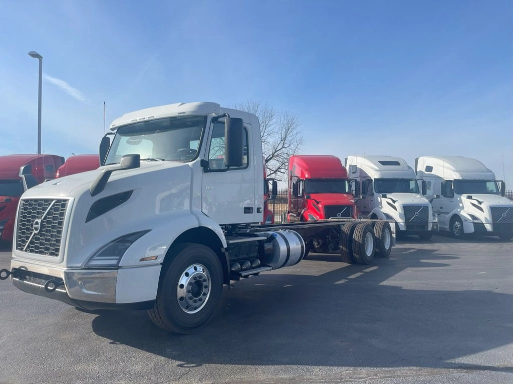 White Volvo VNR day cab chassis shown from the front driver side on a dealership lot.