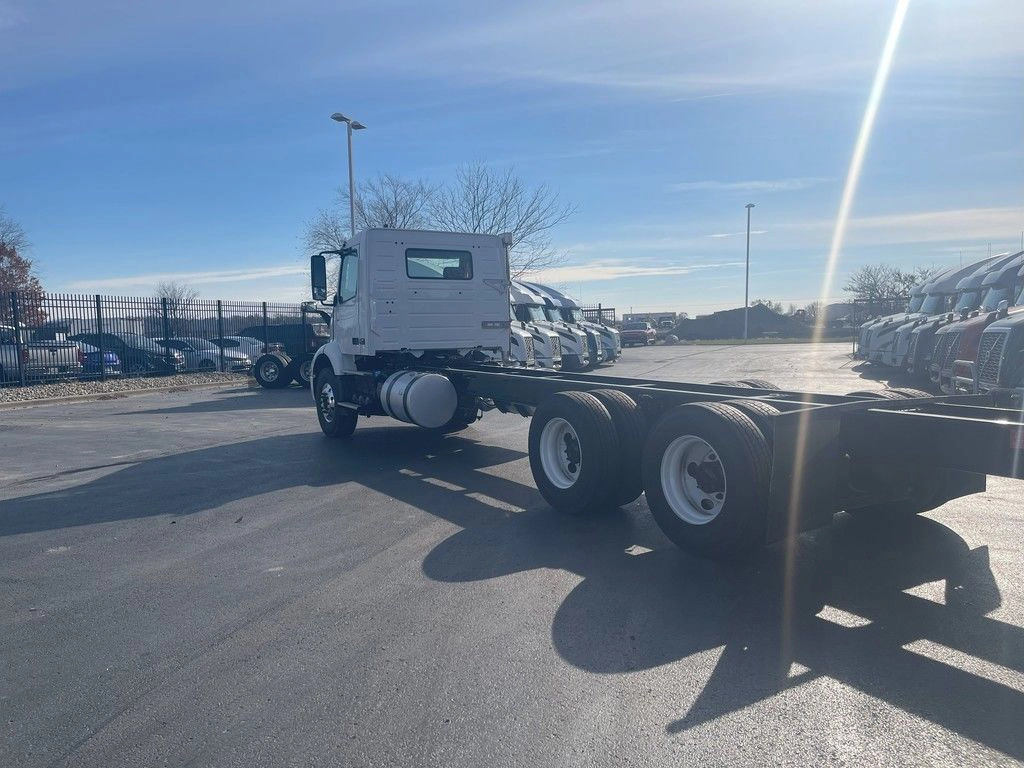 Rear driver-side view of a white Volvo VNR chassis with exposed frame and dual axles.