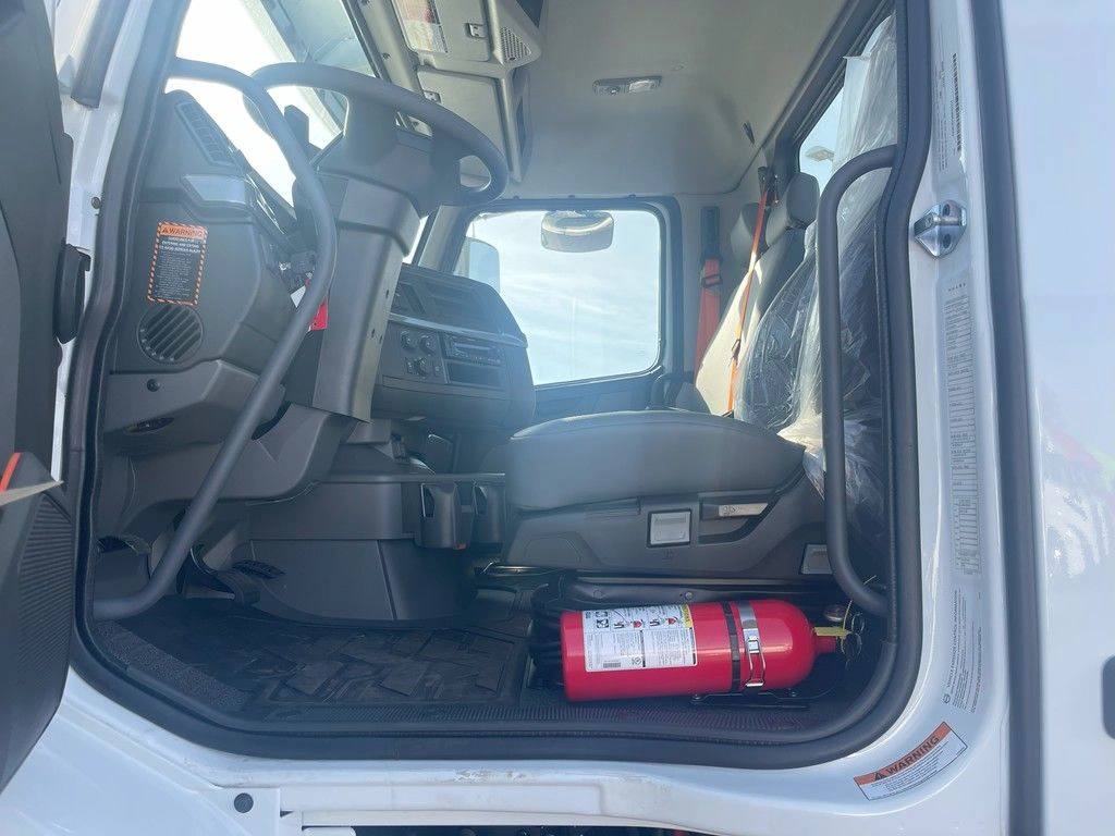 Open cab entry showing the Volvo VNR driver seat, gray interior and red fire extinguisher.