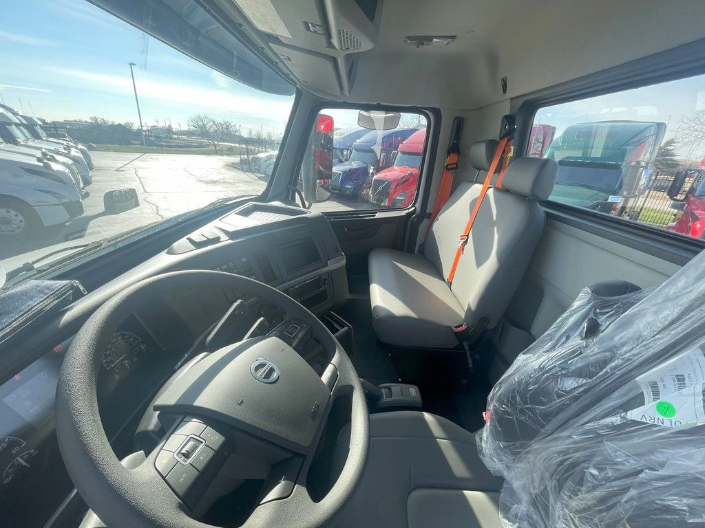 Interior view of the Volvo VNR cab with steering wheel, passenger seat and rear window.