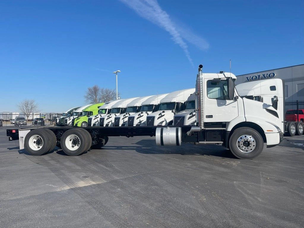 Passenger-side profile of a white Volvo VNR day cab chassis with exposed rear frame rails.