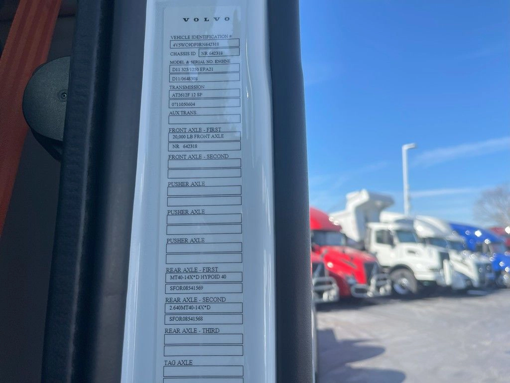Close-up of the Volvo VNR door jamb label with dealership trucks visible outside.
