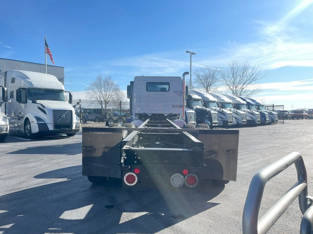 Rear view of a white Volvo VNR chassis showing frame rails, mud flaps and dual tail lights.