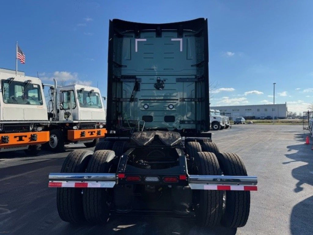 Rear view of a green Volvo VNL sleeper cab showing dual rear axles and fifth wheel in a truck lot.