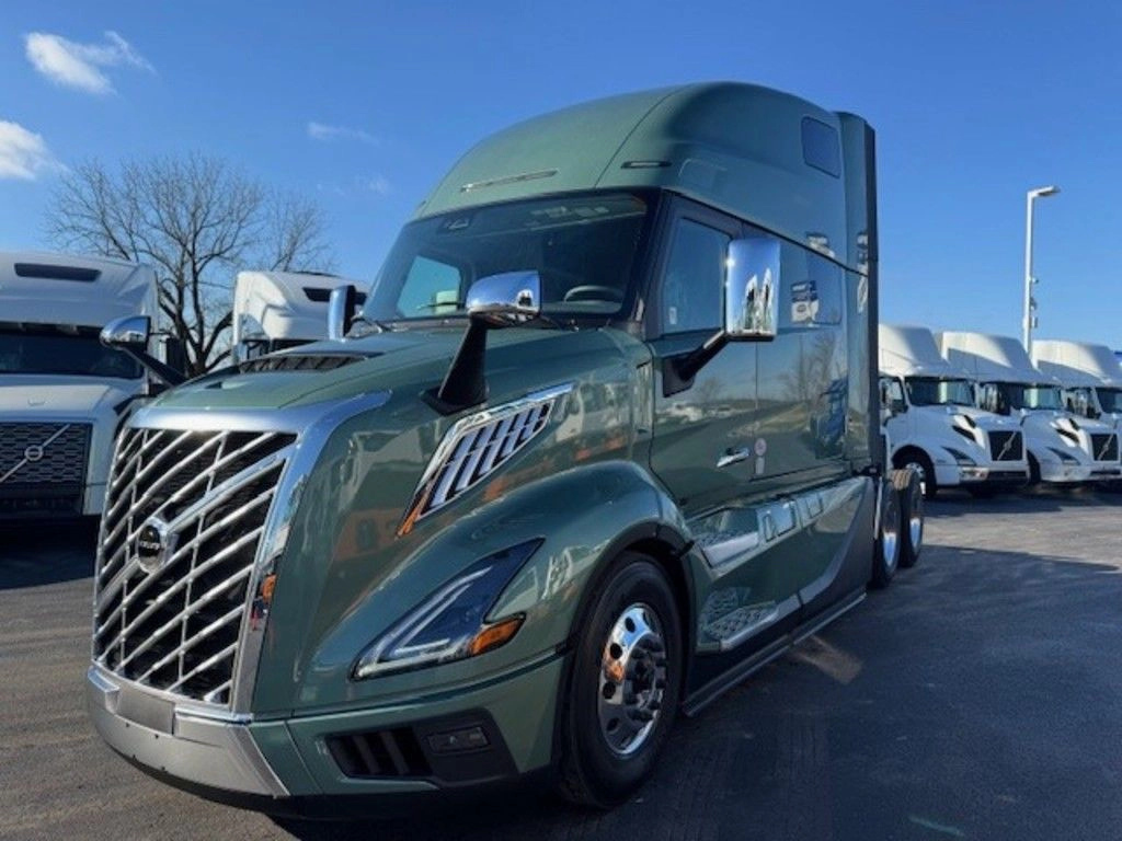 Front three-quarter view of a green 2025 Volvo VNL sleeper truck parked on a dealership lot.
