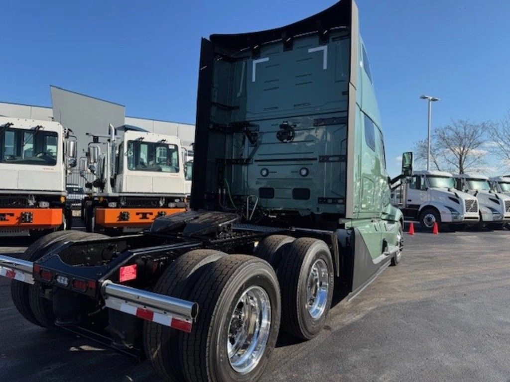Rear three-quarter view of a green Volvo VNL sleeper truck showing tandem axles and fifth wheel area.