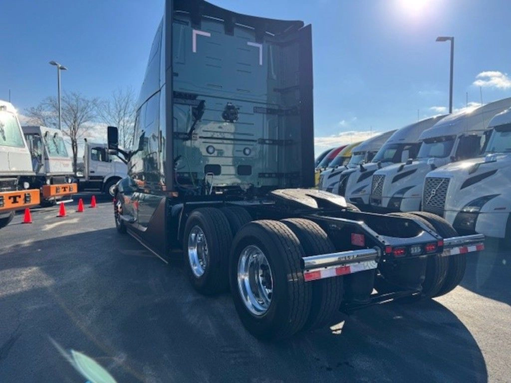 Rear view of a green Volvo VNL sleeper truck parked among other trucks at the dealership.