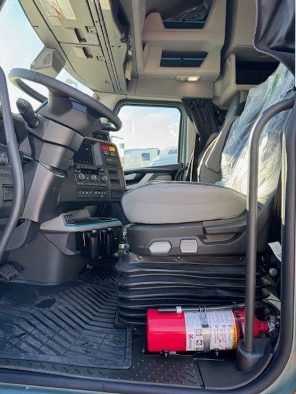 Driver-side cab interior of a Volvo VNL with seat, storage, floor mat and mounted fire extinguisher.