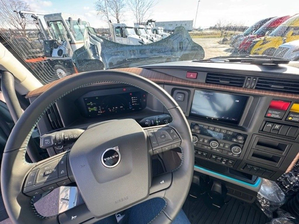 Volvo VNL driver cockpit with steering wheel, digital display, center controls and infotainment screen.