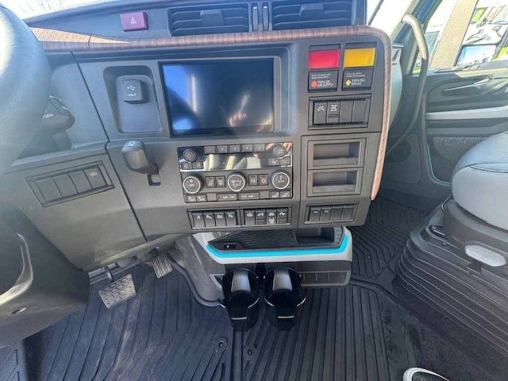 Volvo VNL dashboard with infotainment screen, controls, cup holders and passenger seat.