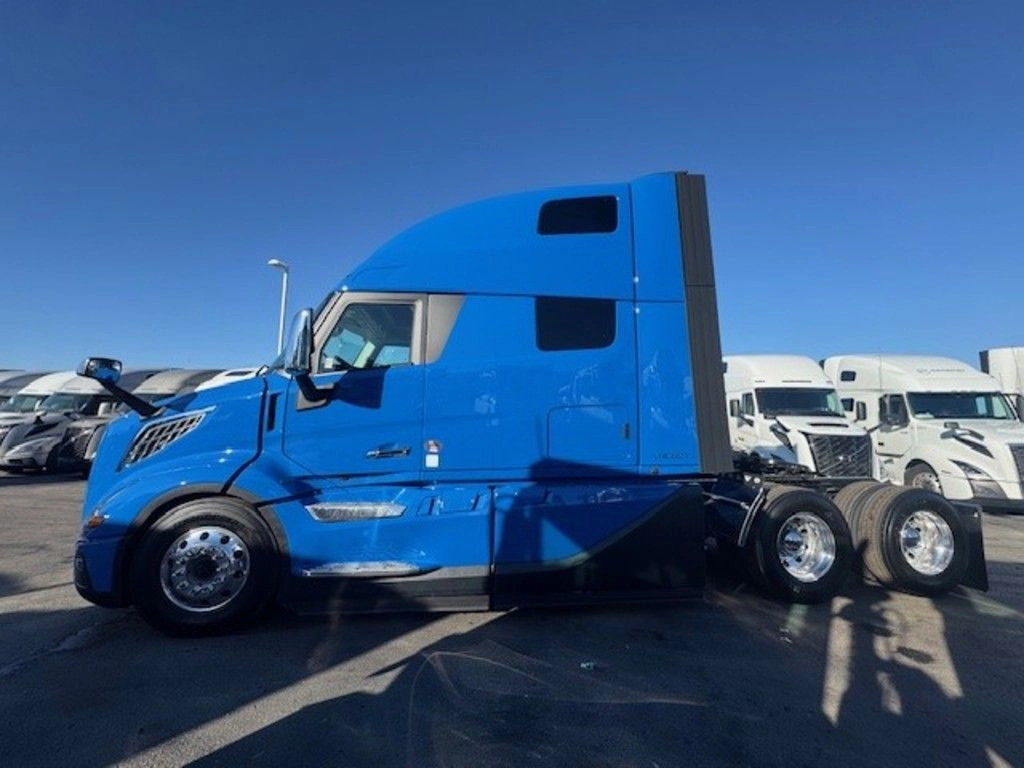 Driver-side profile of blue Volvo VNL sleeper tractor with high-roof cab and tandem rear axles.