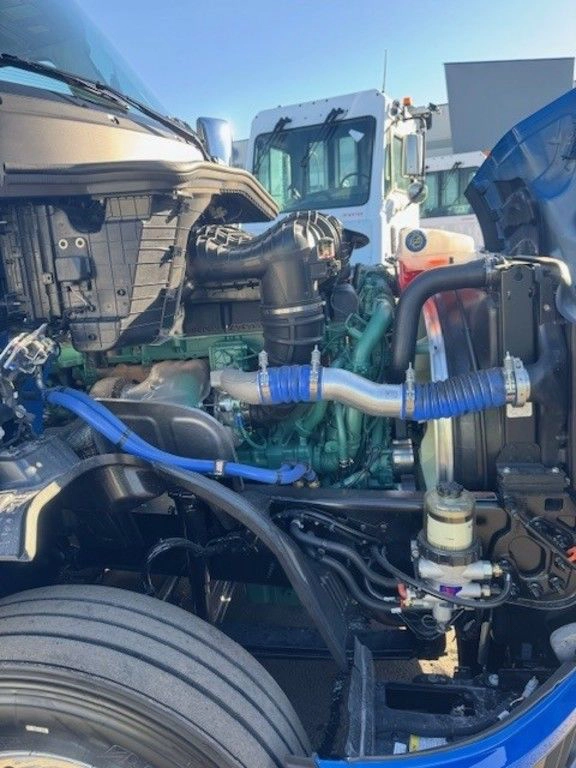 Volvo VNL engine compartment close-up with green engine, intake piping and service components.