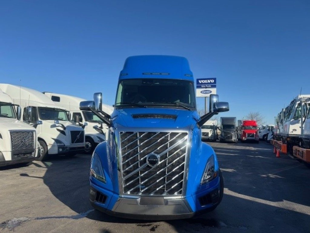 Front view of blue Volvo VNL sleeper tractor with grille, headlights and high-roof cab.