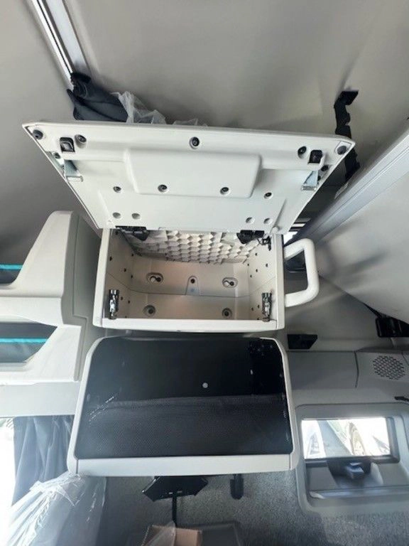 Open overhead storage compartment in Volvo VNL sleeper cab with lower cabinet visible.