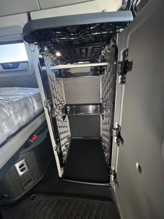 Volvo sleeper cab interior with a narrow storage compartment and bunk area.