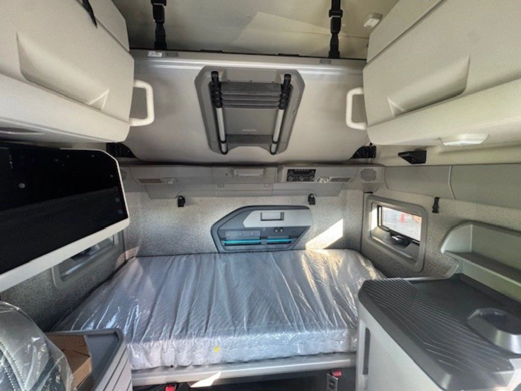 Volvo sleeper cab with bunk bed, overhead storage and side cabinet.