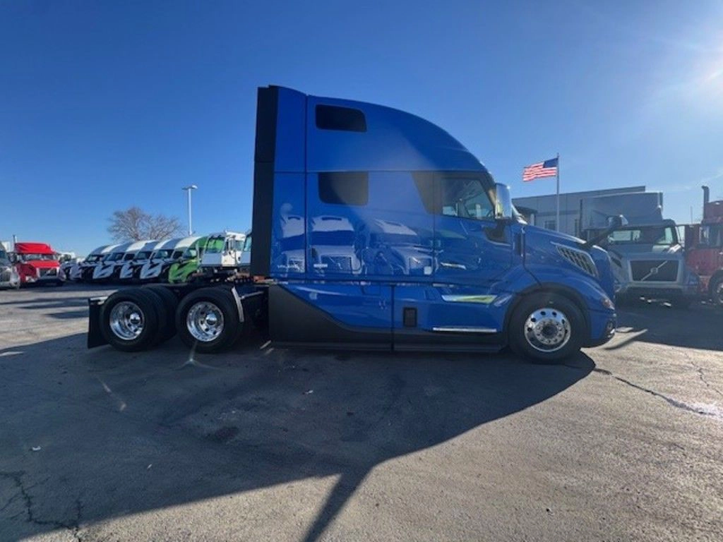 Blue Volvo VNL sleeper truck shown from the passenger side on a dealership lot.