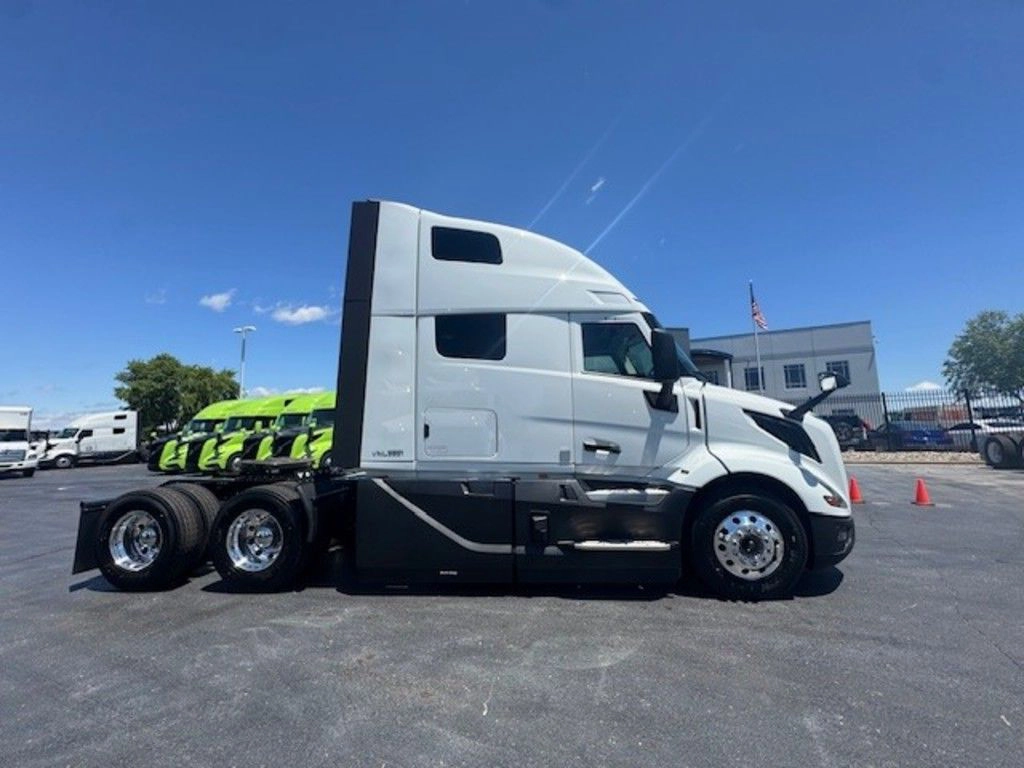 Passenger-side profile of the white Volvo VNL660 sleeper tractor on the truck lot.