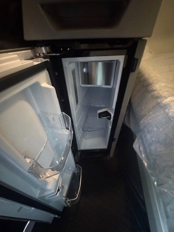 Open refrigerator compartment inside the Volvo VNL660 sleeper cab between the lower storage areas.