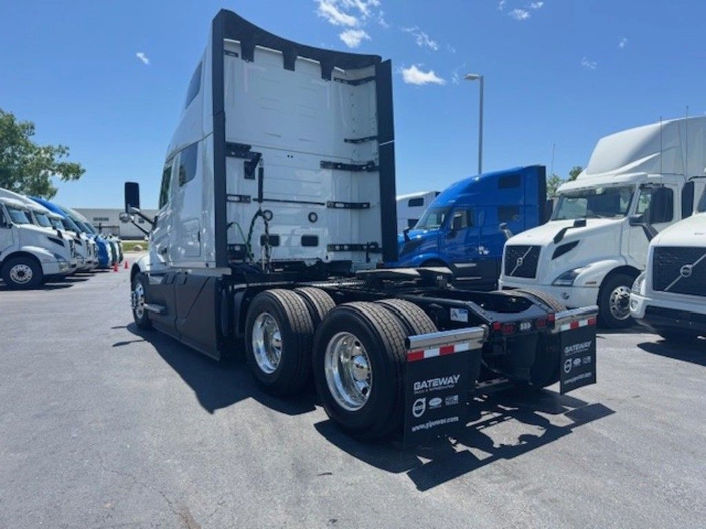 Rear three-quarter view of a white Volvo VNL660 sleeper tractor parked among other trucks on the lot.