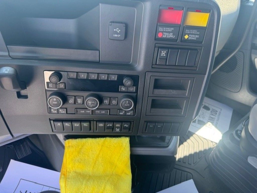 Volvo VNL660 dashboard controls with climate settings, switches and storage compartments.