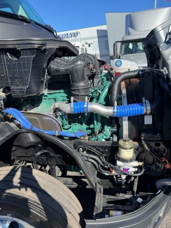 Volvo VNL engine compartment with hood open, showing engine, hoses and service components.
