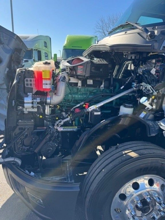 Side view of Volvo VNL engine bay with coolant reservoir, wheel and service components visible.