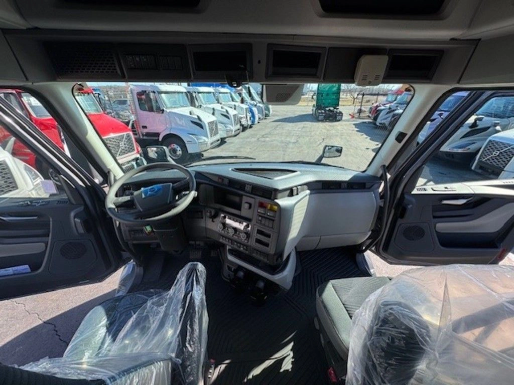 Volvo VNL cab interior with driver and passenger seats, dashboard, steering wheel and wide windshield view.