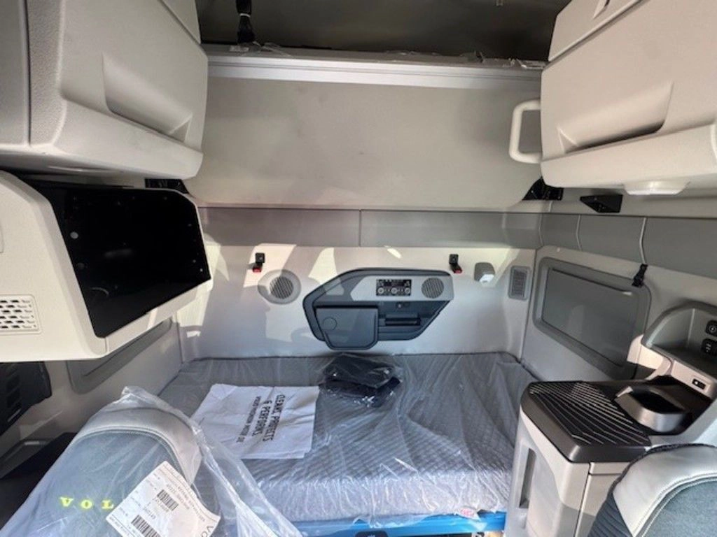 Volvo VNL sleeper area with upper cabinets, wrapped mattress, control panel and built-in storage.