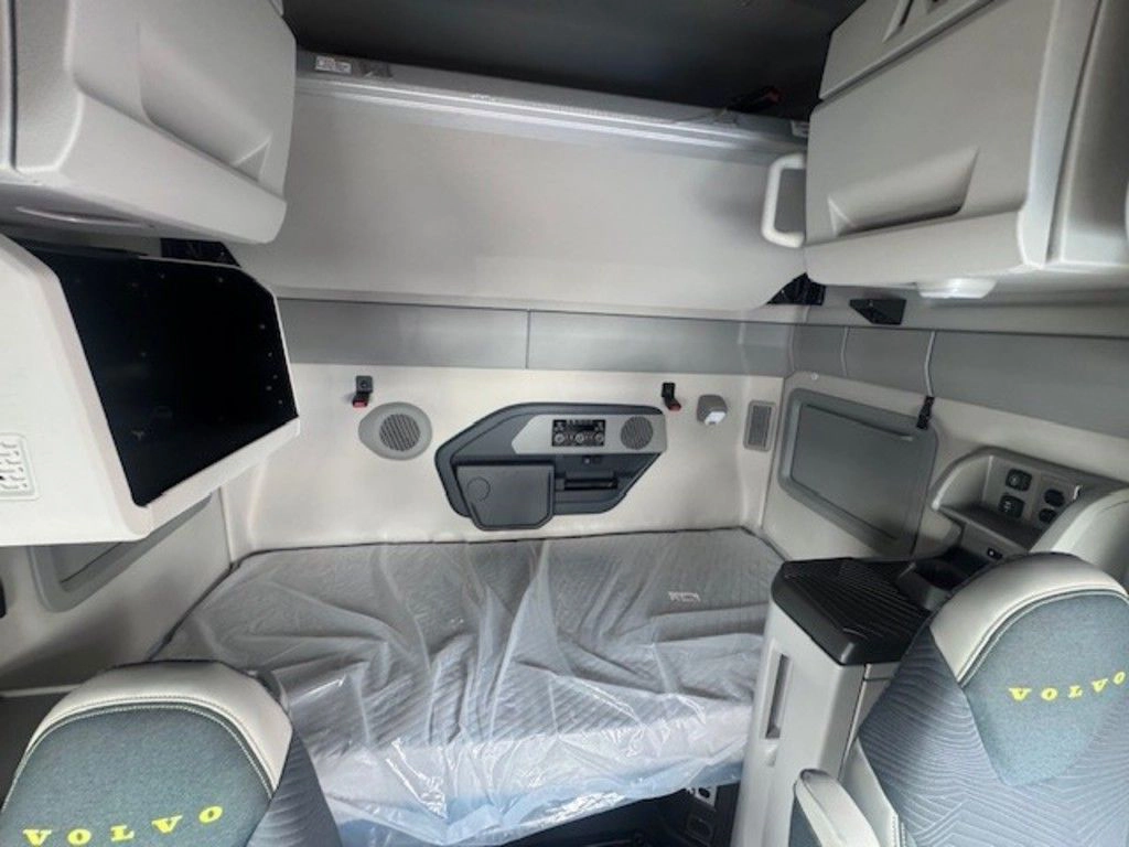 Volvo VNL sleeper area with lower bunk, upper storage cabinets and seats with Volvo branding.