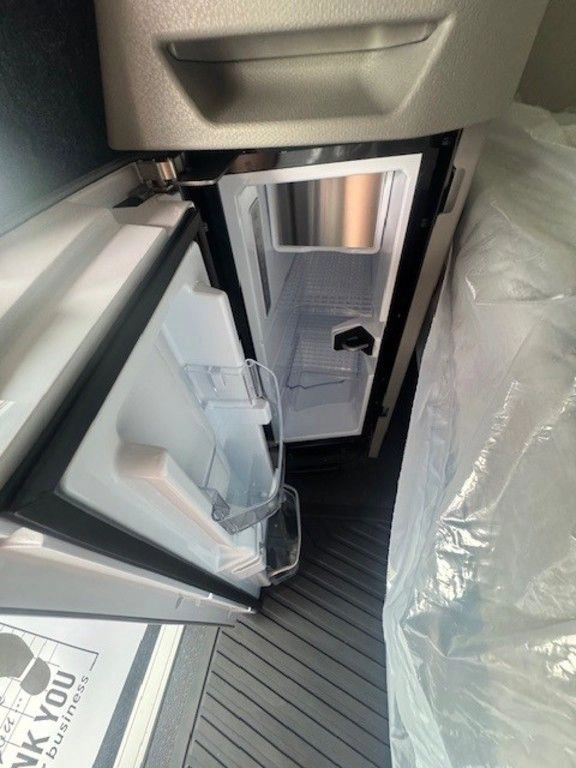 Open refrigerator compartment inside the Volvo VNL sleeper beside the lower bunk.