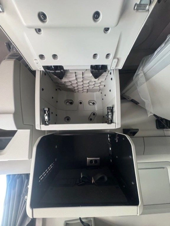 Open sleeper storage compartment in the Volvo VNL with interior mounting points and overhead cabinet door.