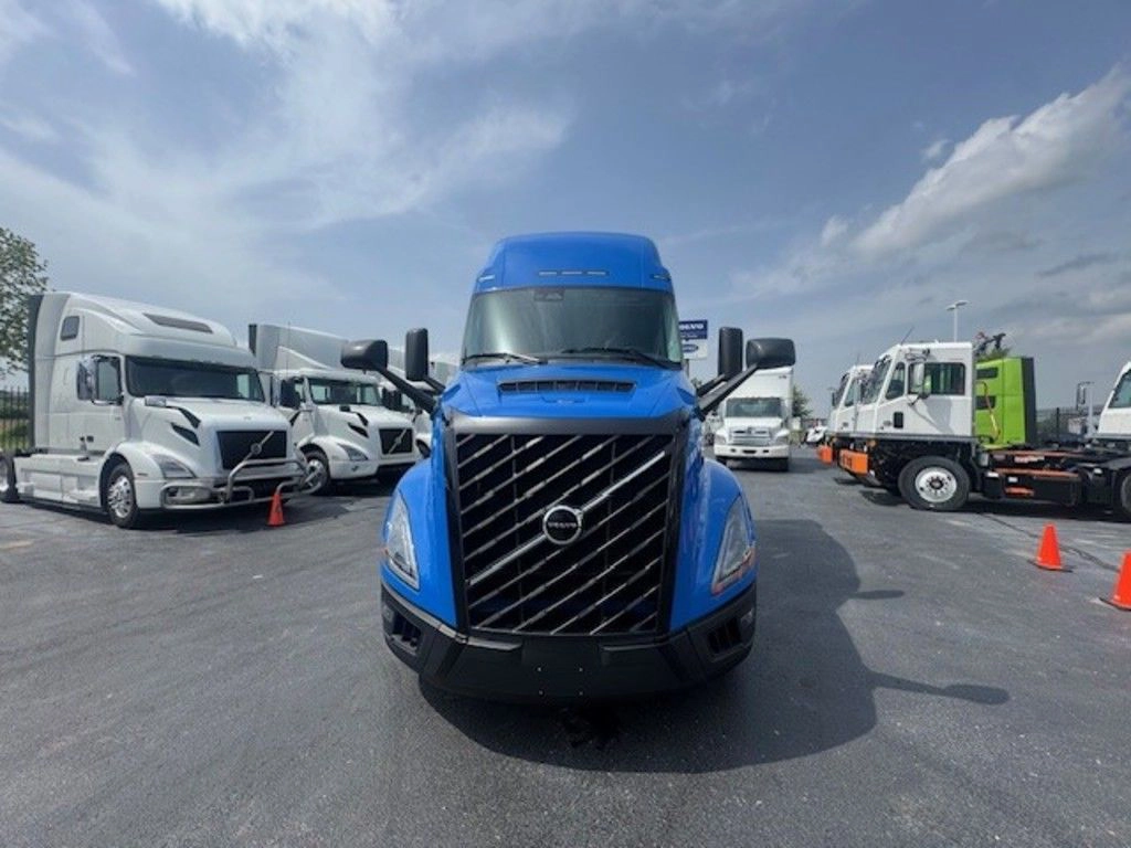 Head-on view of a blue Volvo VNL sleeper truck parked among other trucks at the dealership.