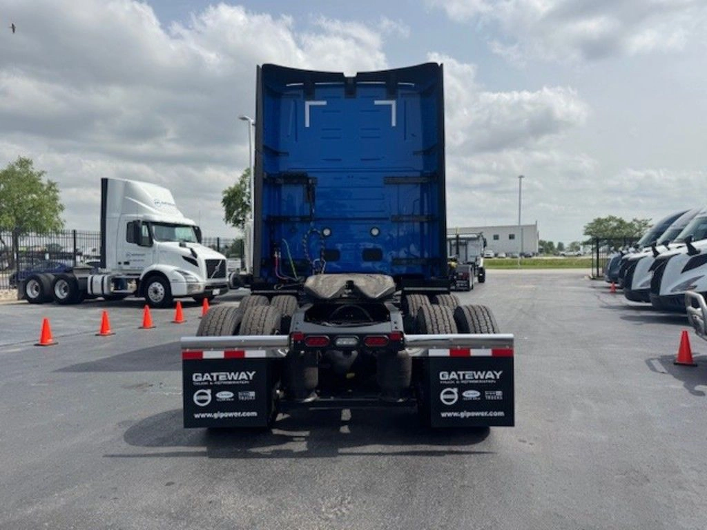 Straight rear view of a blue Volvo VNL sleeper truck showing tandem axles, fifth wheel and mud flaps.