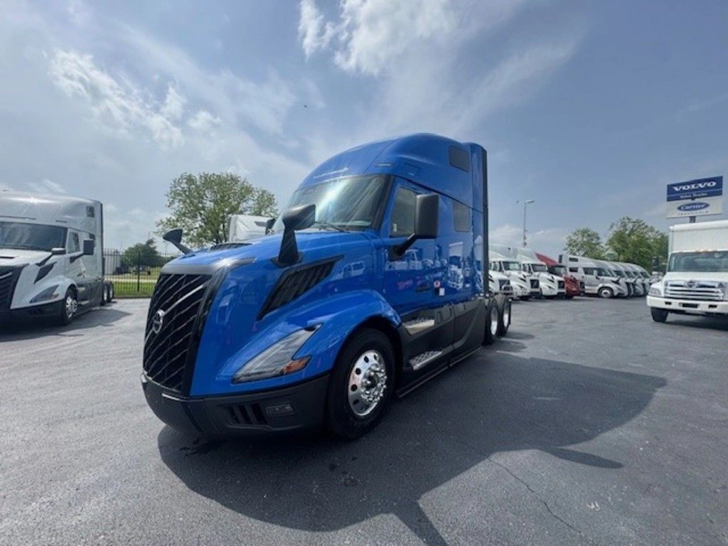 Blue Volvo VNL sleeper truck shown from the front driver side at the dealership lot.