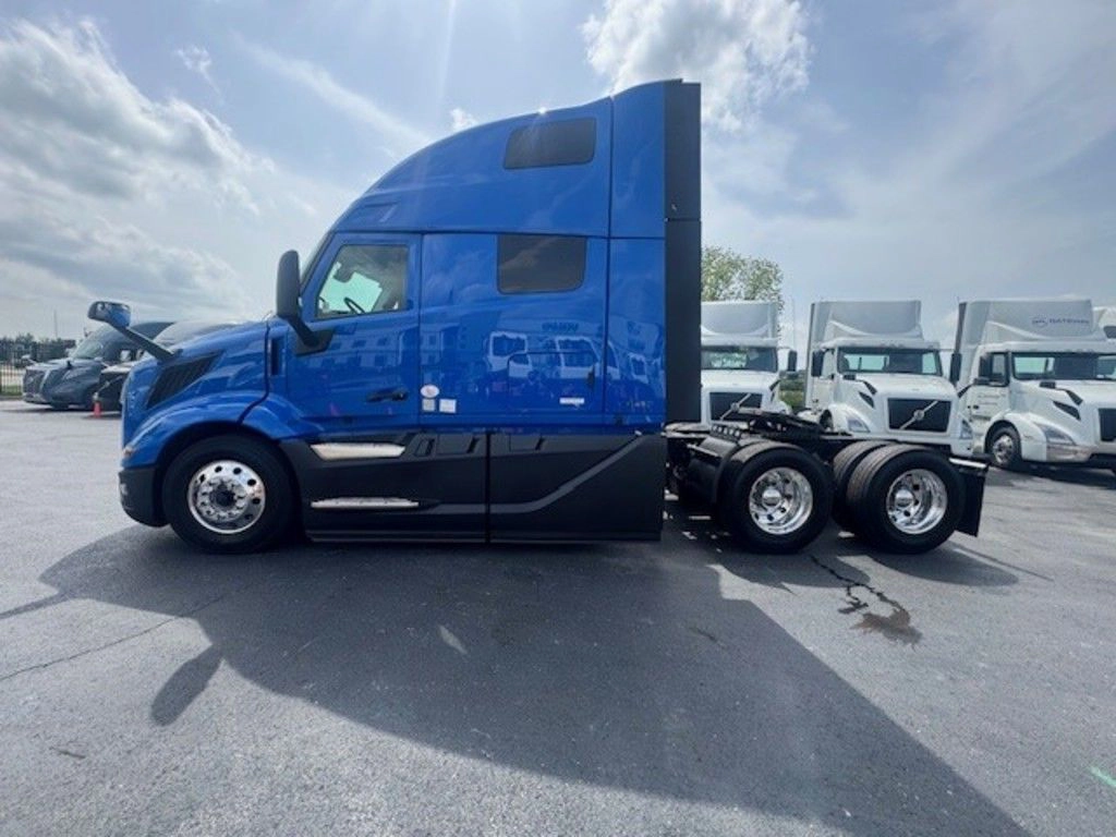 Blue Volvo VNL sleeper truck shown in profile, highlighting the cab, rear axles and clean exterior on the lot.