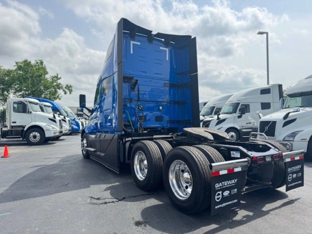 Rear driver-side view of a blue Volvo VNL sleeper truck showing tandem axles and Gateway mud flaps.