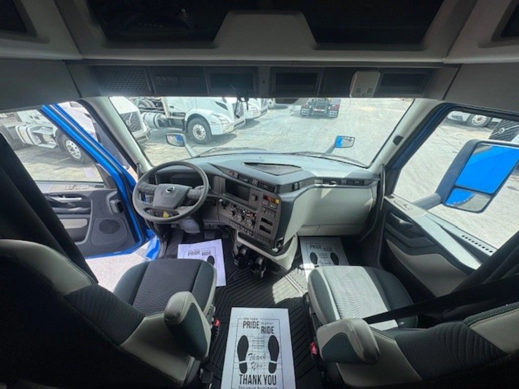 Wide interior view of the Volvo VNL cab showing steering wheel, dashboard, seats and sleeper entry.
