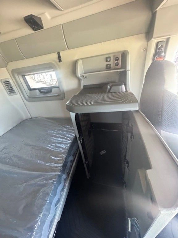 Volvo VNL sleeper interior showing lower bunk, fold-out table, storage cabinets and side window.
