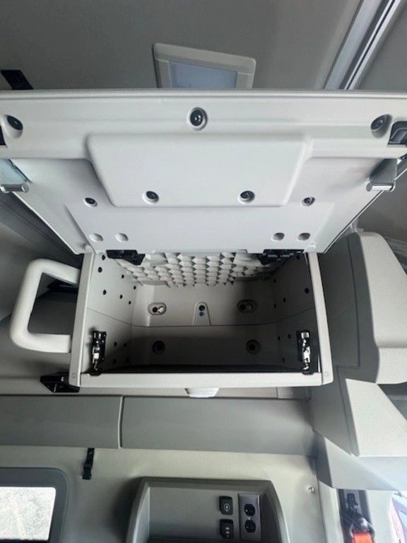 Open overhead storage compartment inside the Volvo VNL sleeper, showing interior shelving and access hardware.