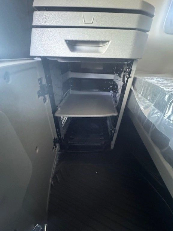 Lower storage compartment inside the Volvo VNL sleeper with pull-out shelf and cabinet access beside the bunk.