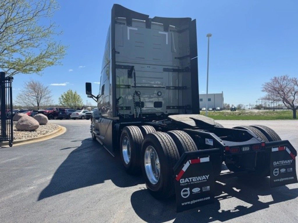 Rear three-quarter view of a Volvo VNL sleeper tractor with tandem axles and fifth wheel on a paved dealership lot.
