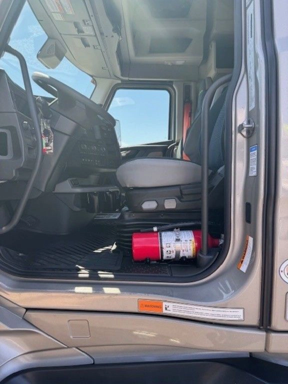 Driver-side cab entry of a Volvo VNL showing the seat, floor area and mounted fire extinguisher.