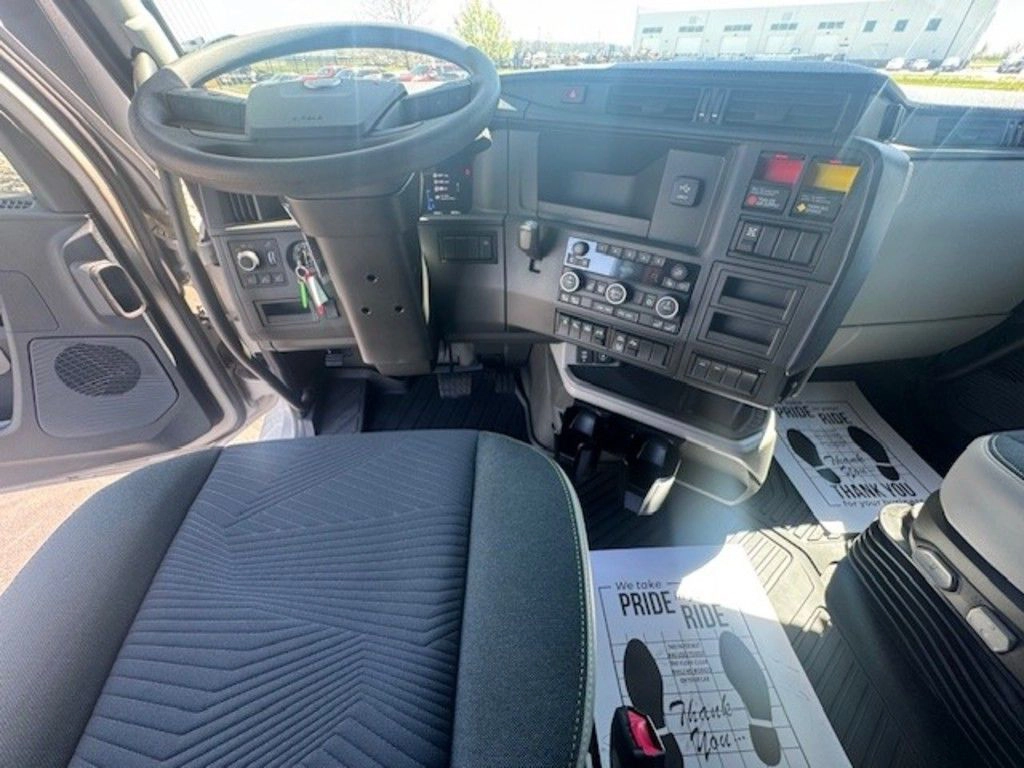 Volvo VNL driver cockpit with steering wheel, center controls, radio and dashboard storage visible.