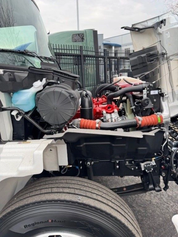 Close-up of the Hino L6 engine bay from the driver side, showing coolant reservoir, hoses and engine components.