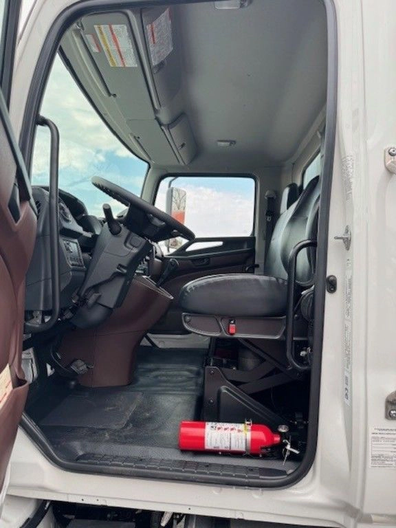 Interior view of the Hino L6 cab from the open driver door, showing the seat, steering wheel and fire extinguisher.