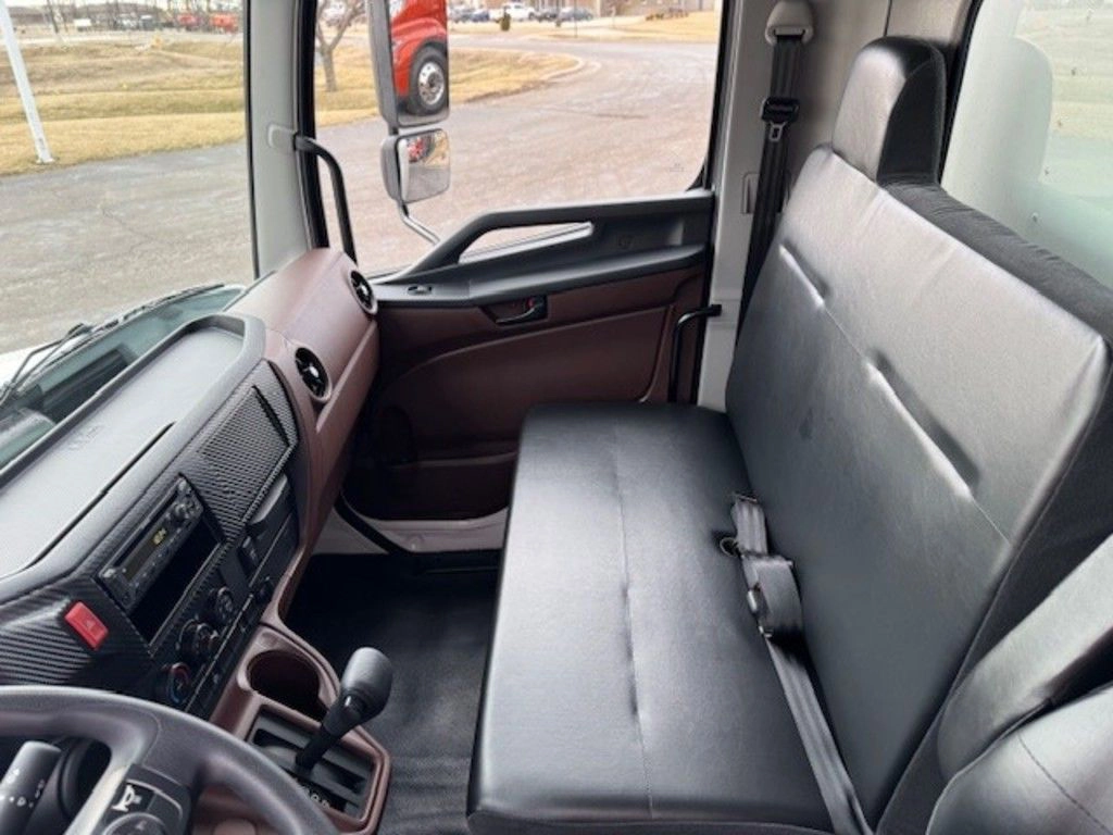 Hino L6 cab interior with gray bench seat, dashboard controls and manual gear selector visible.