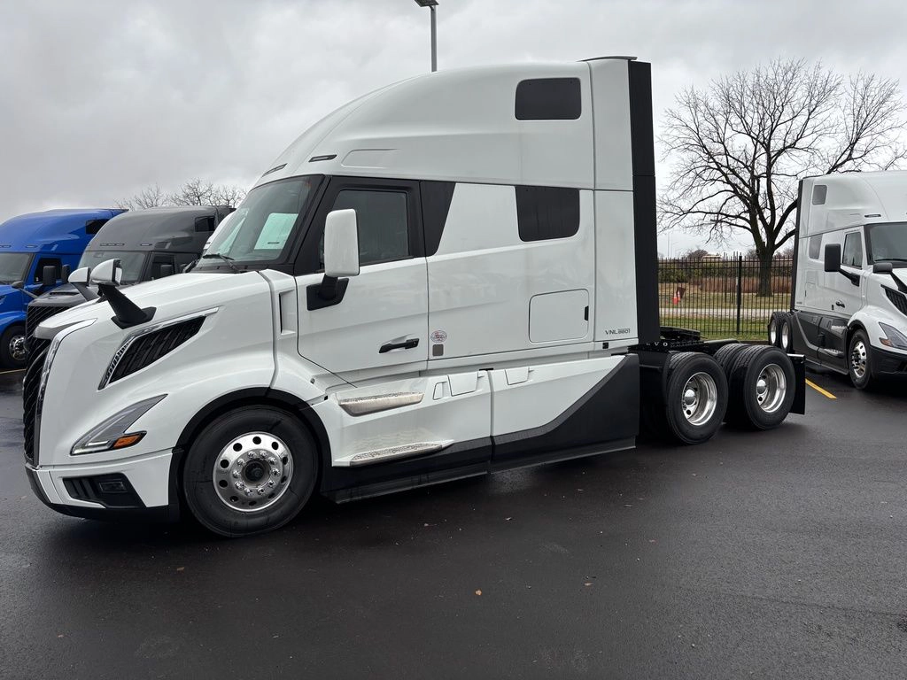 White Volvo VNL sleeper truck shown from the driver side on a dealership lot.
