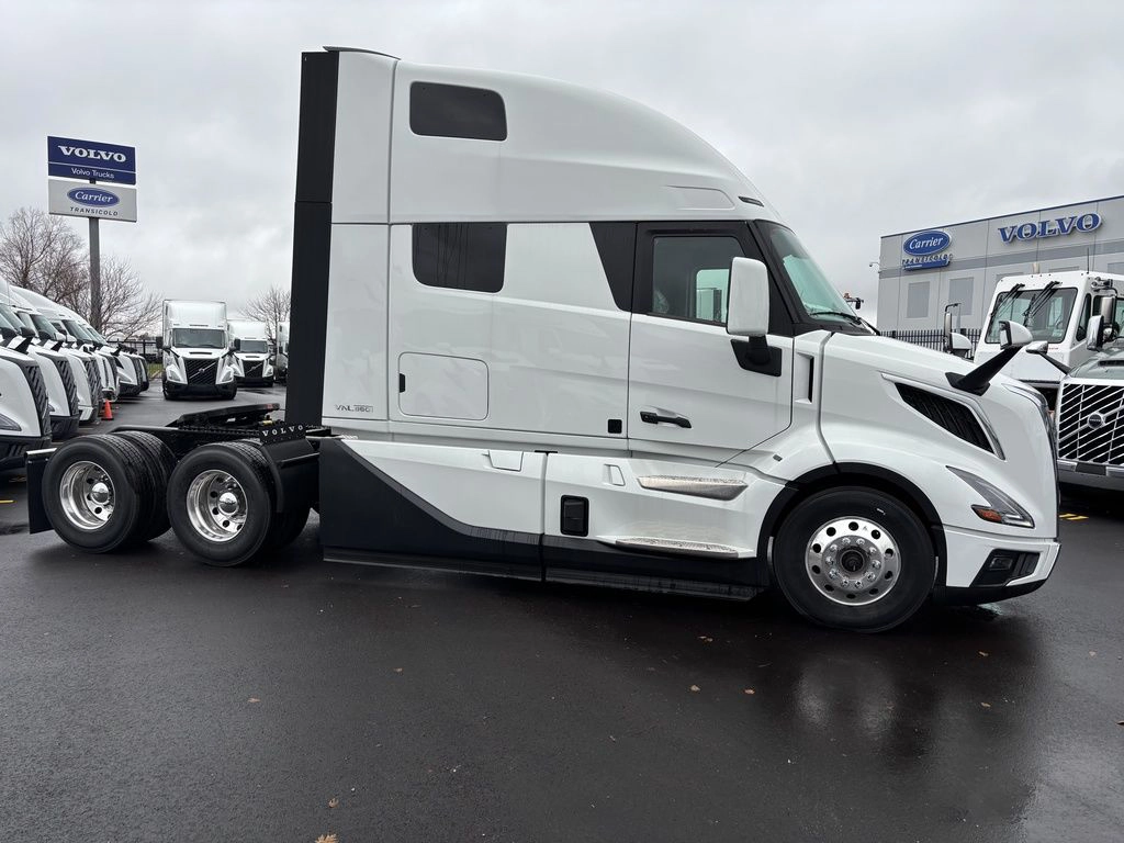 White Volvo VNL sleeper truck shown from the passenger side on a dealership lot.